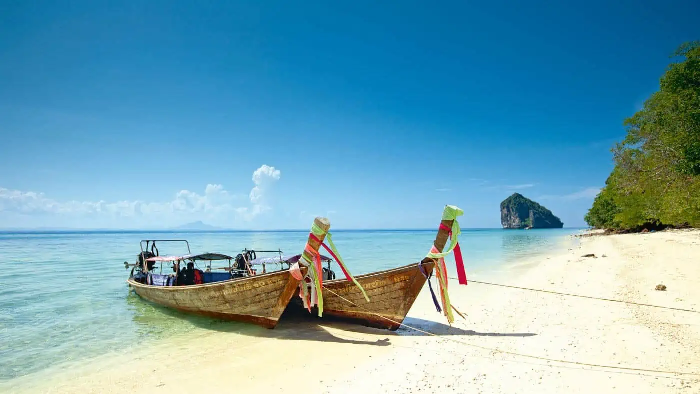 Longtail boats and limestone cliffs on the Andaman coast of Thailand